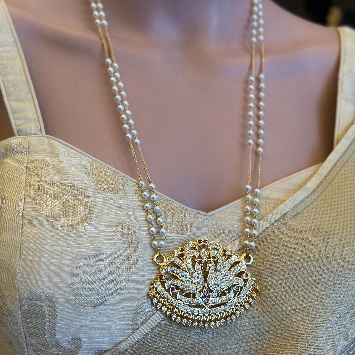 Peacock
South Indian Impoun Padakkam necklace featuring an intricate peacock pendant with white stones.
