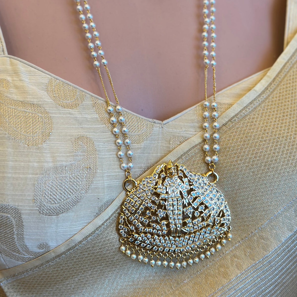 Temple 
Traditional gold-tone Impoun Padakkam necklace with temple-inspired pendant and white stone detailing.